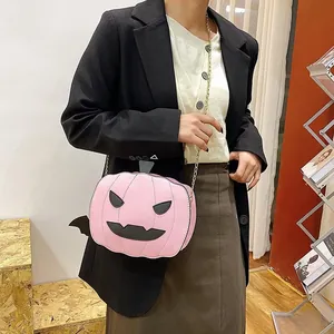 Pink pumpkin crossbody bag with bat wings and gold chain strap shown on a model