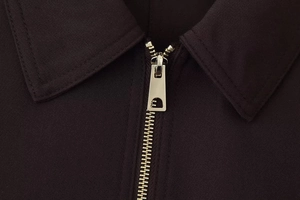 Close-up of premium metal zipper and high-density twill fabric on a dark brown jacket