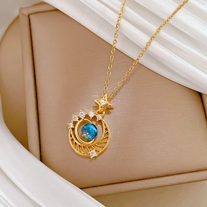 Detailed macro view of gold star and moon necklace with a deep blue spherical gemstone