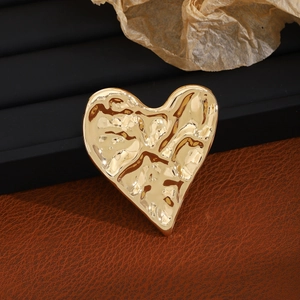 Vintage golden irregular hammered heart brooch on leather background with luxury aesthetic