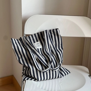 Sac fourre-tout en toile à rayures verticales bleu marine sur une chaise blanche