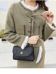 Detail of retro black crossbody bag with clover print and silver flower lock on model