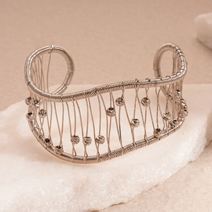 Gros plan du bracelet manchette en fil argenté avec perles à facettes sur pierre