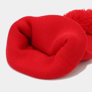 Winter red knitted Christmas beanie with large pom-pom and thick ribbed texture