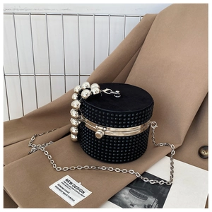 Detail of black cylindrical handbag with rhinestones and unique silver metal ball handle
