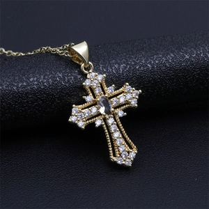 Macro shot of gold cross pendant necklace featuring brilliant white zircons and center gem