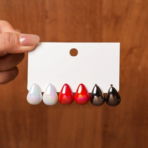 Detail view of teardrop acrylic earring set in white, red, and black on a display card