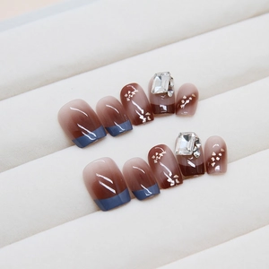 Brown gradient press-on nails with blue French tips and crystal rhinestone accents