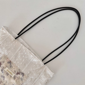Detailed macro view of off-white lace texture canvas bag with purple butterfly pattern