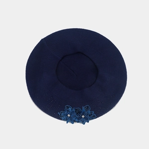 Close-up detail of dark blue knitted beret with rhinestone flower appliques and texture