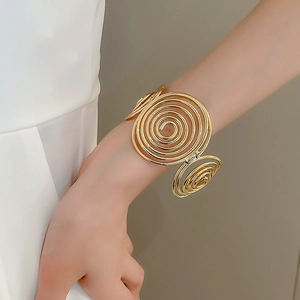 Close-up of golden wavy layered spiral metal cuff bracelet on model's wrist
