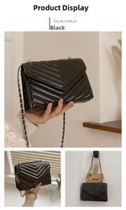 Detail of black patent leather small square bag featuring V-shaped quilting and chain strap