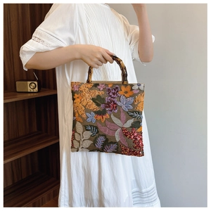 Linen tote bag with sequin floral embroidery and bamboo handle held by a model
