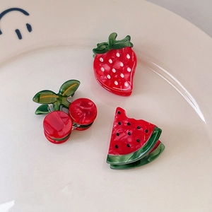 Set of cute strawberry, cherry, and watermelon fruit hair clips on a ceramic plate