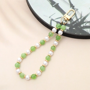 Detail of green and white beaded phone strap with gold spacers and metal clasp