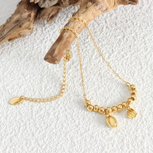 Chinese style gold lotus bead bracelet in stainless steel on a rustic wooden stand