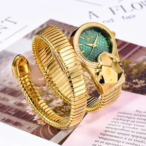 Macro detail of golden snake-shaped watch with green dial and diamond-set bezel on magazine