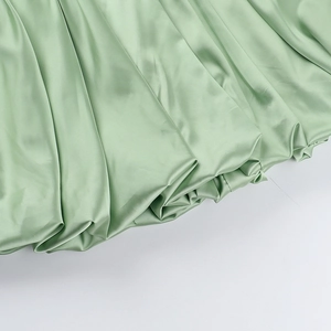 Close-up of light green satin fabric detail showing smooth texture and pleated design