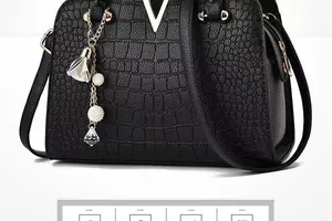 Detail view of black embossed faux crocodile leather handbag with silver V-shaped hardware