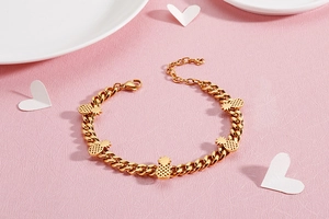 Close-up of golden pineapple bracelet with chunky Cuban chain and hollow charms