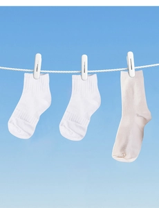 Detail of white cotton socks hanging on clothesline against a clear blue sky