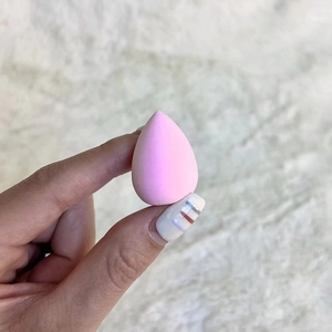 Close-up of pink teardrop beauty sponge showing fine texture on marble background