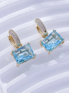Close-up of gold earrings with rectangular sea blue stones and micro-pave zirconia crystals