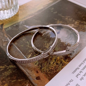 Artistic detail of two silver bracelets with zircon stones on a vintage paper background