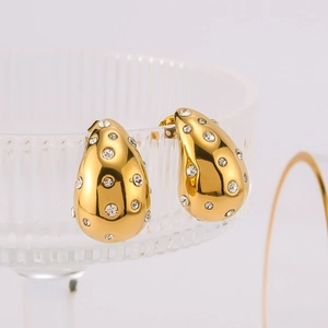 Ins style gold hollow teardrop earrings with crystals on a glass display stand