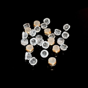 Close-up of clear silicone bullet earring backs with gold metal rings on a black background