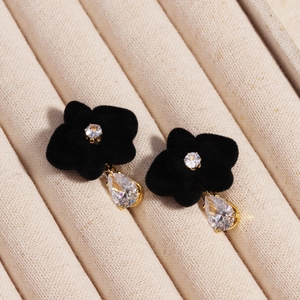 Detail of black velvet flower earring with sparkling zircon stone and gold droplet pendant