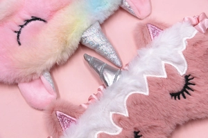 Macro detail of plush unicorn sleep masks with rainbow gradient and silver laser horns
