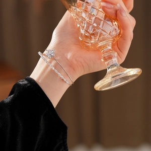 Détail du bracelet à fleurs en zircon argenté porté à la main tenant un verre