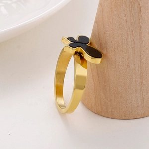 Detailansicht goldener Edelstahlring mit schwarzem Schmetterling auf Holzständer