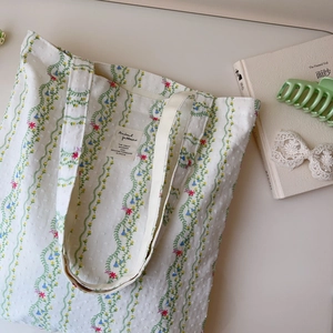 Detail of floral canvas tote bag showing green vine patterns and jacquard texture