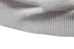 Detail of light gray knitted sweater featuring elastic ribbed hem and premium cotton texture