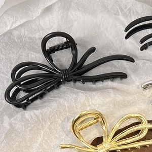 Detailed view of metal bow-knot hair claws in black, gold, and silver finishes