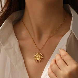 Close-up of a gold-plated necklace featuring a smiling sun pendant on a beaded chain
