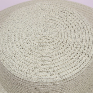 Macro view of detailed concentric spiral weaving on a cream-colored foldable straw hat base