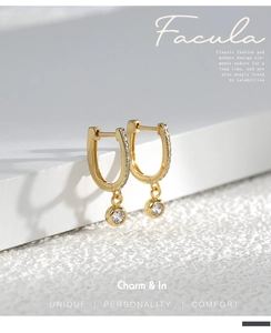 Macro detail of U-shaped gold plated brass earrings with micro-inlaid cubic zirconia crystals