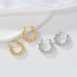 Macro detail of gold and silver twisted knot stainless steel hoop earrings for women