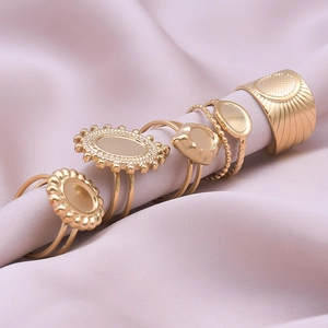 Five-piece gold geometric oval stainless steel ring set on soft lavender fabric