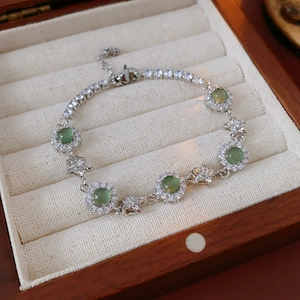 Gros plan détaillé d'un bracelet fleur en argent avec pierres vertes et zircons