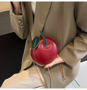 Detailed view of red apple-shaped crossbody bag with leaf detail and metal chain strap