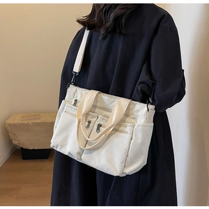 Off-white corduroy shoulder bag shown on model with multiple zipper pockets and straps