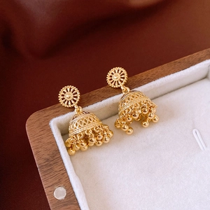 Macro detail of 14K gold plated Jhumka bell tassel earrings with intricate vintage pattern