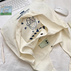 Detail of canvas tote bag interior with pocket showing phone and makeup storage