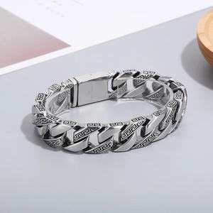 Macro detail of vintage silver stainless steel cuban link bracelet with Greek key patterns