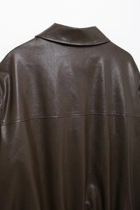 Detailed close-up of collar and shoulder seams on a brown faux leather bomber jacket