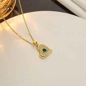 Close-up of golden heart pendant necklace with emerald green zircon and white diamonds